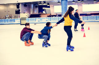 Teens skating pulling each other on ice