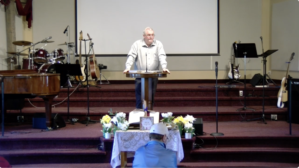 Rev Scott Cross stands behind the pulpit and speaks on Psalm 46, the Psalm of Confidence.